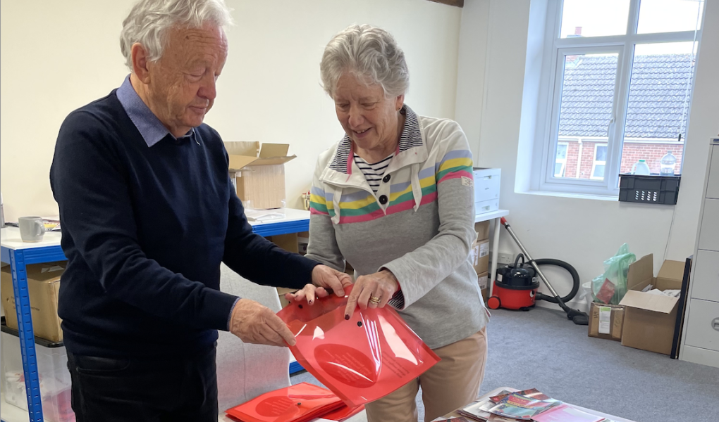 Two volunteers making information packs