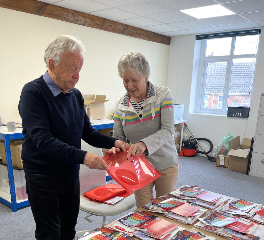 Two volunteers making information packs